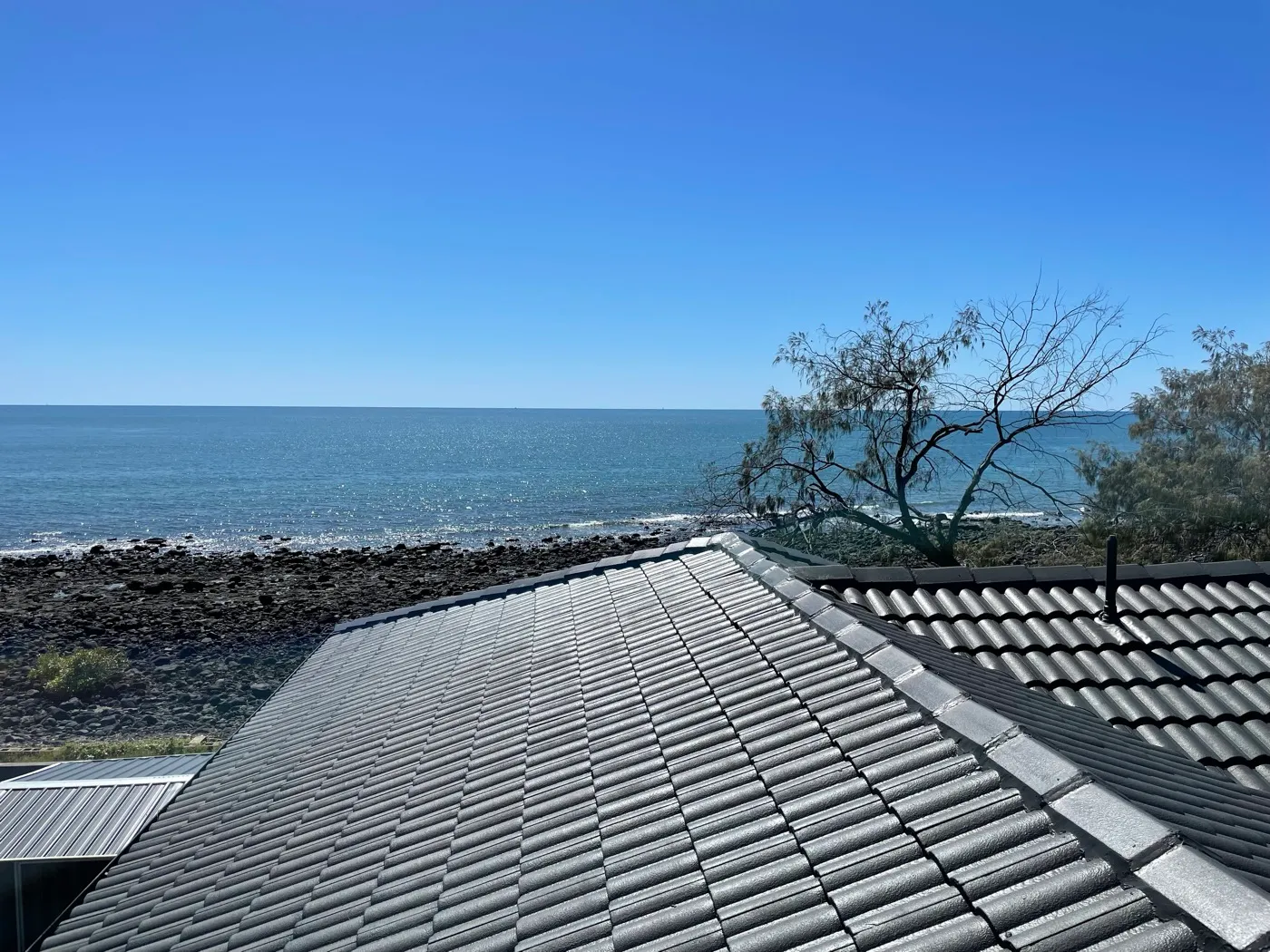 A charcoal concrete-tile roof on the Bundaberg beachfront insulated with cellulose fibre to keep the coastal sun out — Innes Park