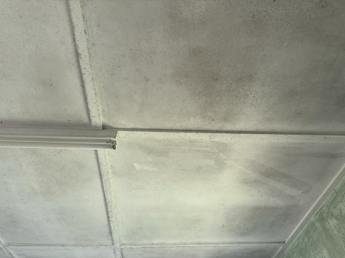 Dark mould spreading in patches and lines across a fibro ceiling, mapping the cold strips where there is no insulation behind the plaster for warm moist air to condense on — found on a Comfort Zone roof inspection