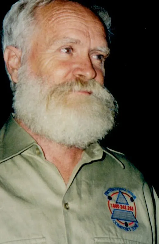 Peter Johnson's father, grey-bearded, wearing the original embroidered 'Protecting your Comfort Zone' work shirt — the family insulation trade, a generation back