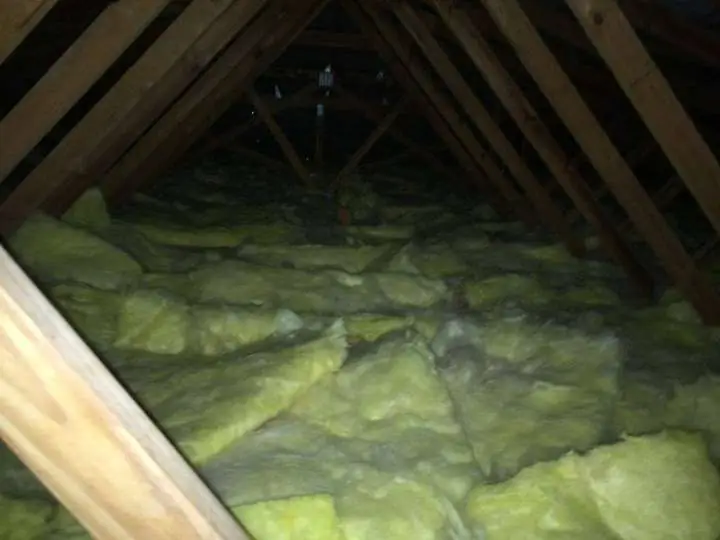 Yellow fibreglass batts laid unevenly with gaps across ceiling joists, a poor competitor installation