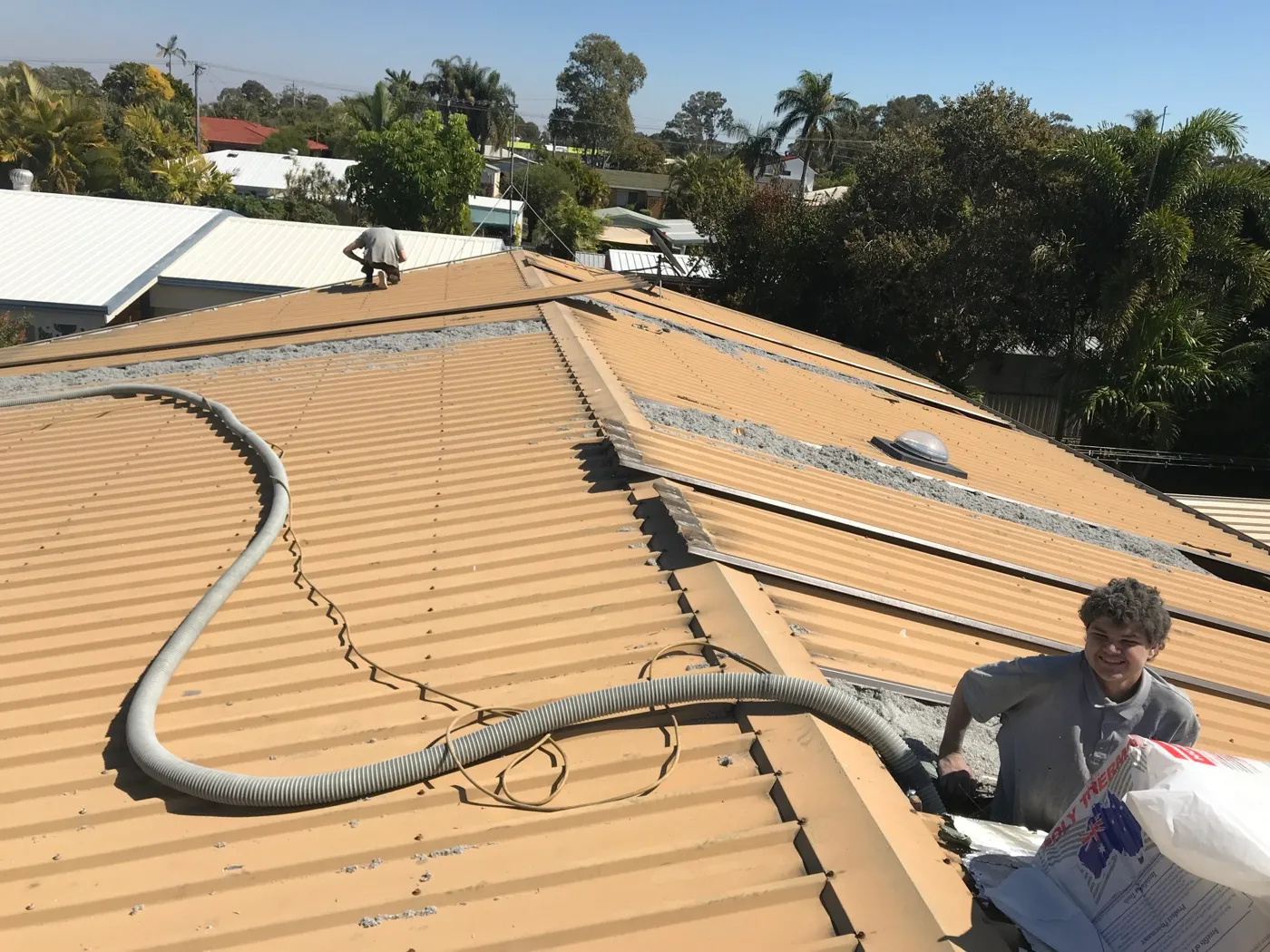 A Comfort Zone crew member blowing cellulose insulation straight into the open roof cavity of a Pialba home — Hervey Bay