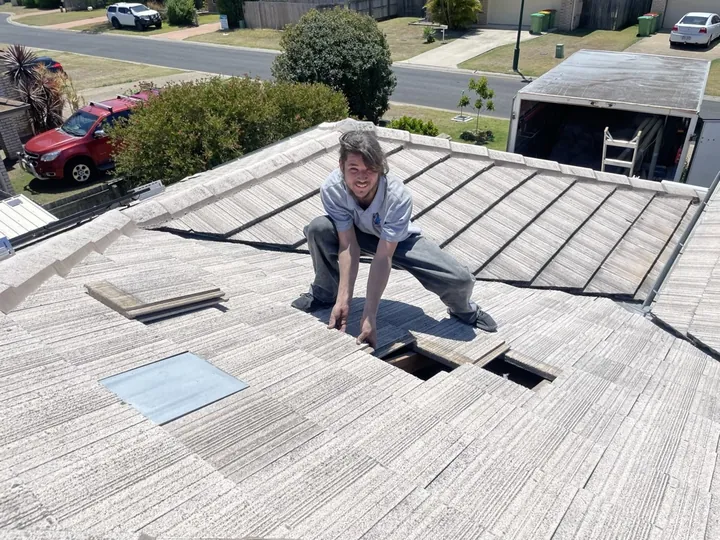 A Comfort Zone installer carefully replacing flat concrete roof tiles over an access opening after a ceiling insulation job