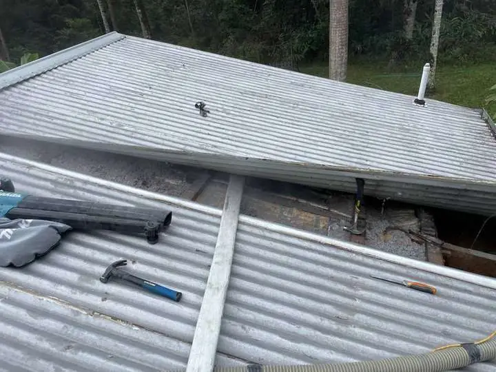 A Comfort Zone installer's tools on a corrugated iron roof with the ridge opened to pump cellulose into a raked section, Mount Burrell