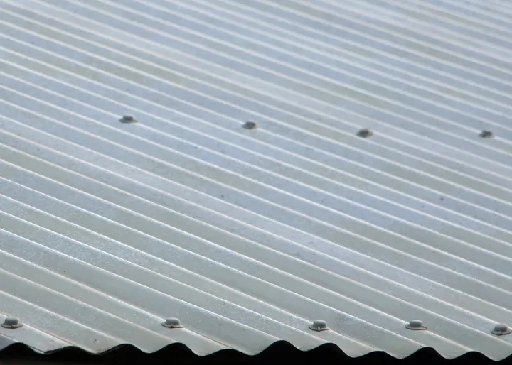Close-up of a silver corrugated iron / ColorBond metal roof showing the rounded ribs and tek screws, the most common metal roof in SE QLD