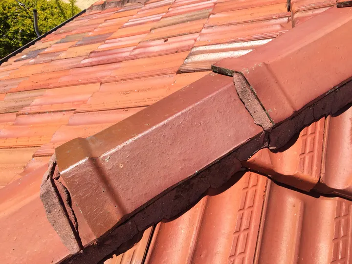 Cracked cement pointing on the ridge capping of a Brisbane terracotta-tile roof, the sort of roof fault Comfort Zone flags during its free roof check