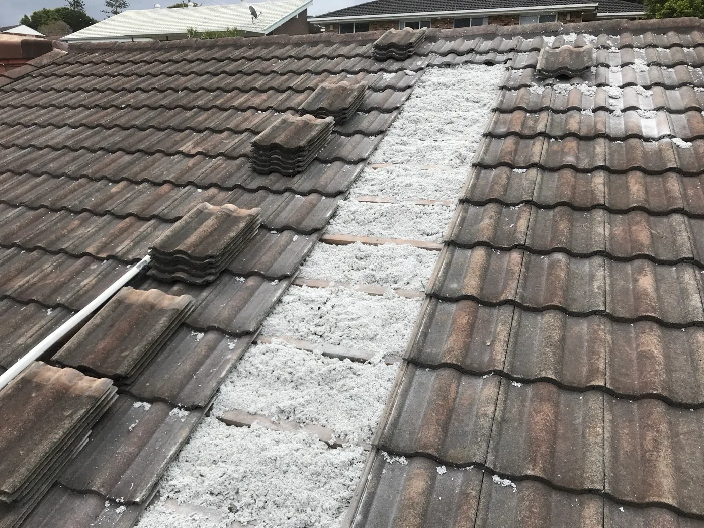 Cellulose insulation packed between the battens of a concrete-tile roof, topped up from above the tiles — Tweed Heads